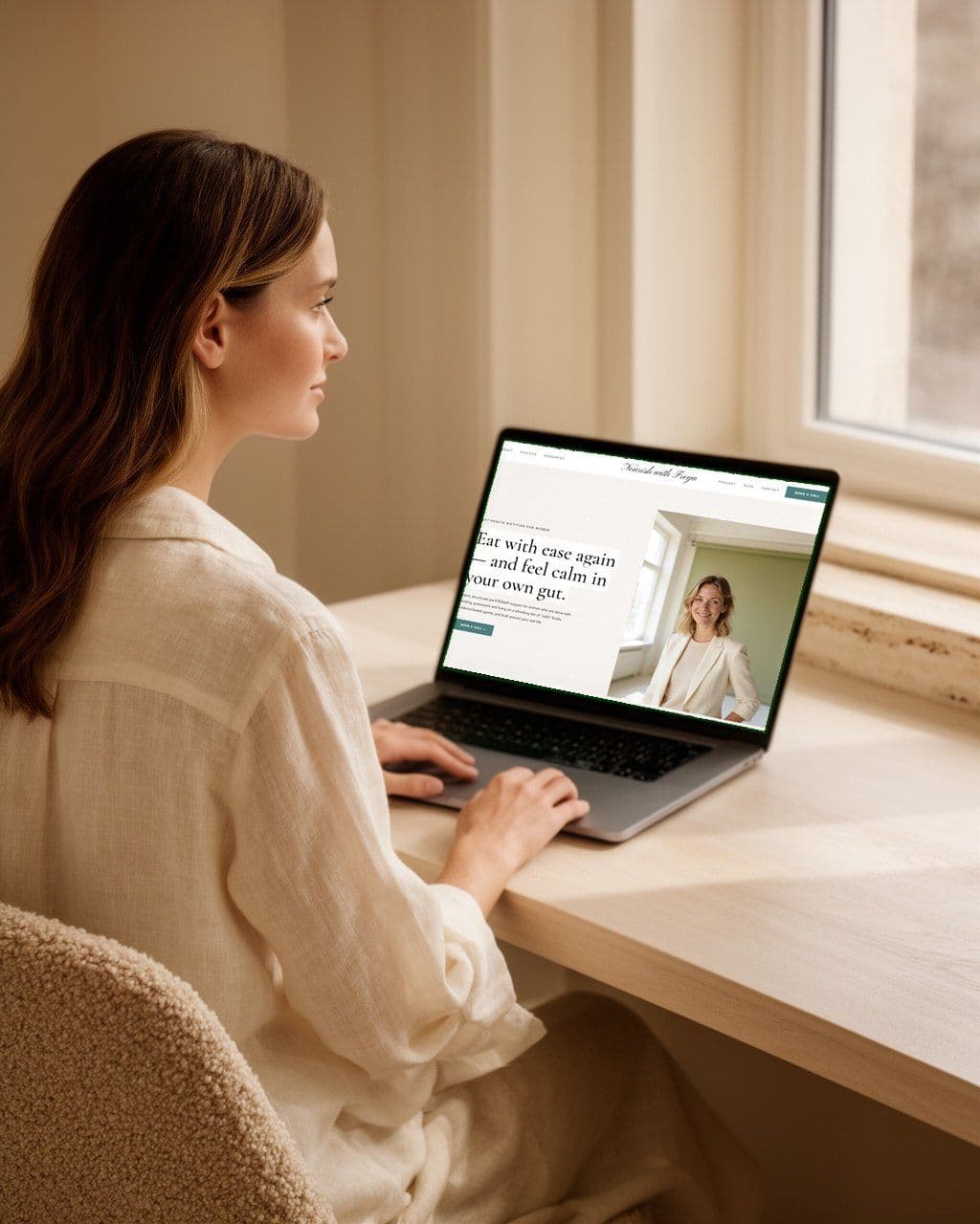 A woman at a desk clicking through a website draft on her laptop